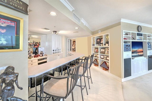 kitchen featuring crown molding, white cabinets, a breakfast bar area, and light tile floors