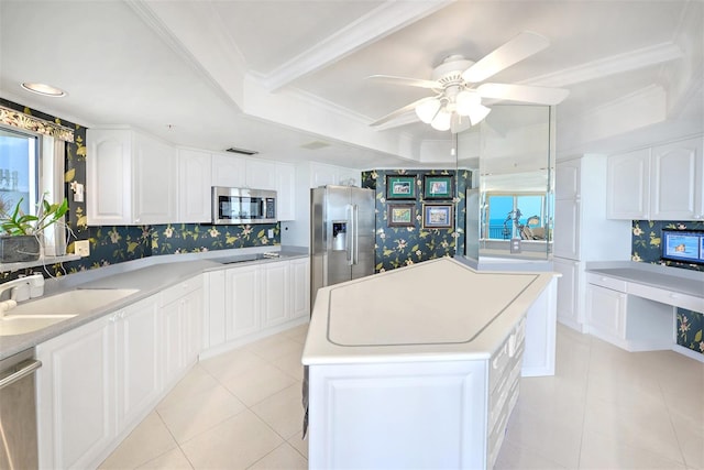 kitchen featuring ceiling fan, tasteful backsplash, stainless steel appliances, a raised ceiling, and a center island