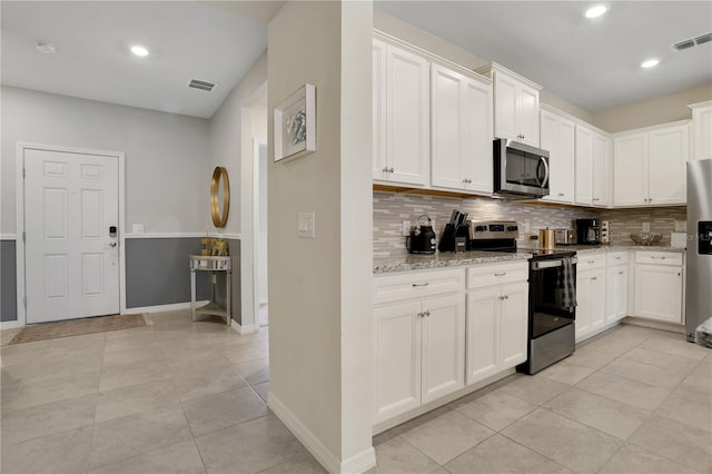 kitchen featuring stainless steel appliances, light stone counters, tasteful backsplash, and light tile floors