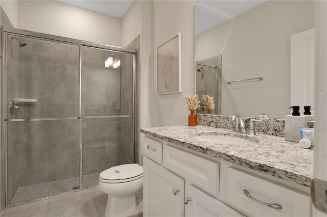 bathroom featuring tile flooring, vanity with extensive cabinet space, a shower with shower door, and toilet