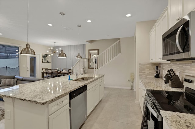 kitchen with stainless steel appliances, white cabinetry, tasteful backsplash, and a kitchen island with sink