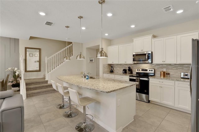 kitchen with backsplash, a center island with sink, appliances with stainless steel finishes, and hanging light fixtures