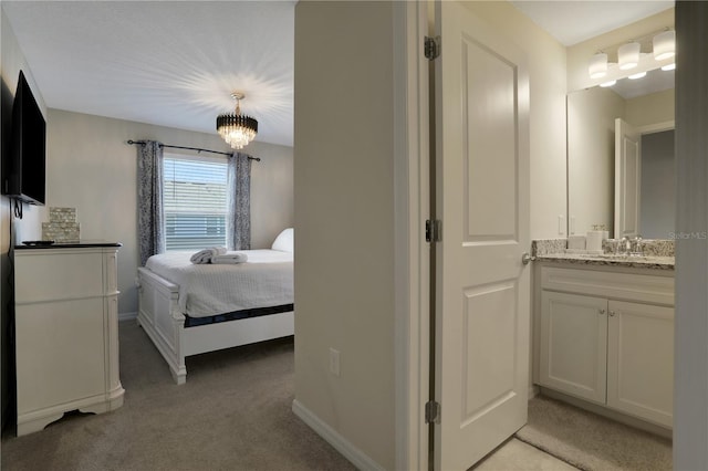 bedroom featuring a chandelier, sink, and carpet