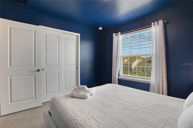 carpeted bedroom with a closet and a textured ceiling