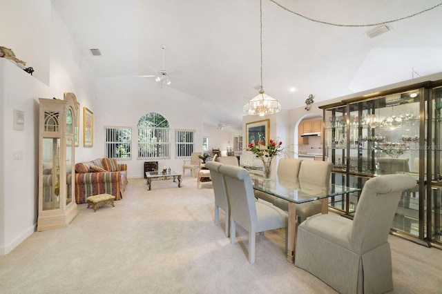 carpeted dining room with high vaulted ceiling and ceiling fan with notable chandelier