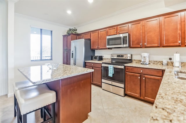 kitchen with light stone counters, crown molding, a kitchen bar, light tile patterned floors, and appliances with stainless steel finishes