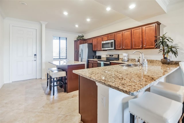 kitchen featuring light stone countertops, sink, stainless steel appliances, a kitchen breakfast bar, and kitchen peninsula