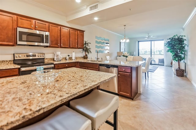 kitchen with a kitchen breakfast bar, ornamental molding, stainless steel appliances, sink, and decorative light fixtures