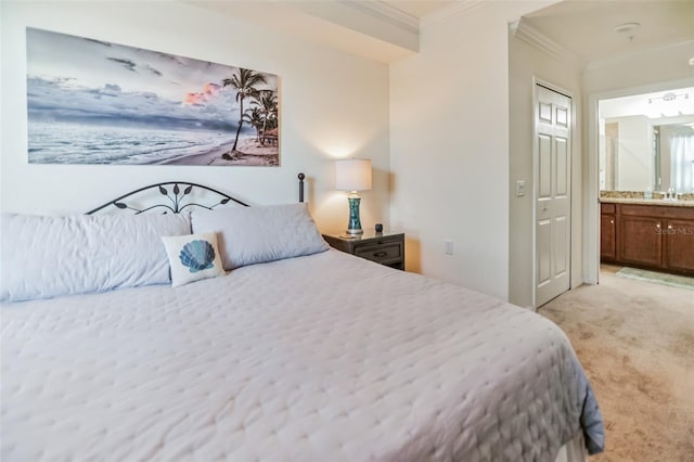 carpeted bedroom featuring ensuite bath, ornamental molding, and sink