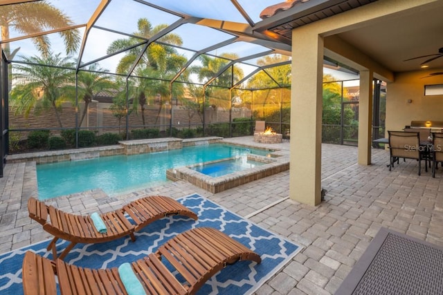 view of pool featuring a fire pit, an in ground hot tub, pool water feature, glass enclosure, and a patio area