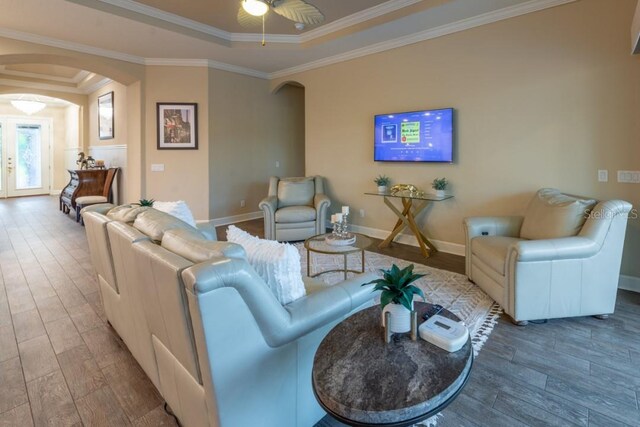 living room featuring ceiling fan, a raised ceiling, crown molding, and wood-type flooring