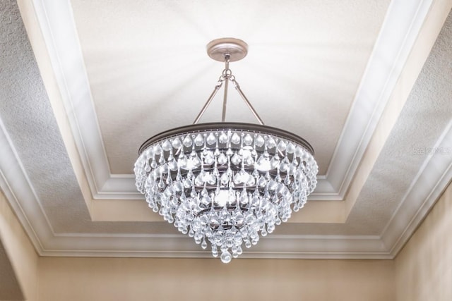 details featuring crown molding, a raised ceiling, and a notable chandelier