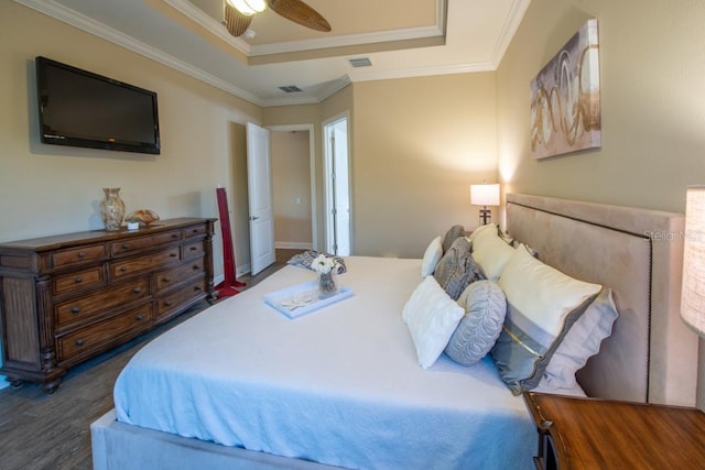 bedroom with crown molding, a tray ceiling, dark hardwood / wood-style floors, and ceiling fan