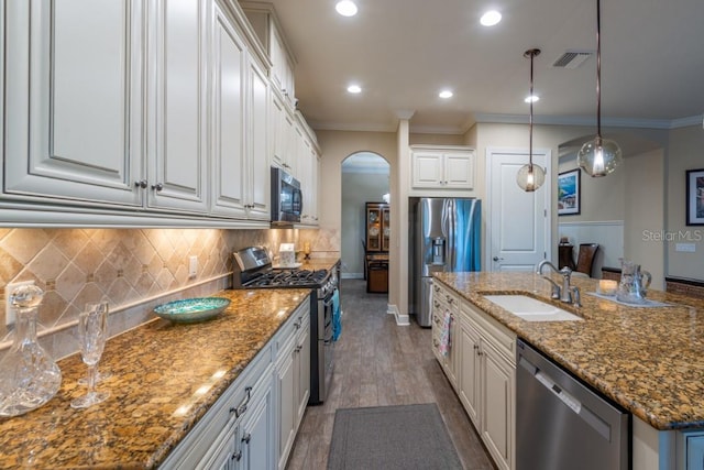 kitchen with sink, white cabinetry, decorative light fixtures, appliances with stainless steel finishes, and a kitchen island with sink