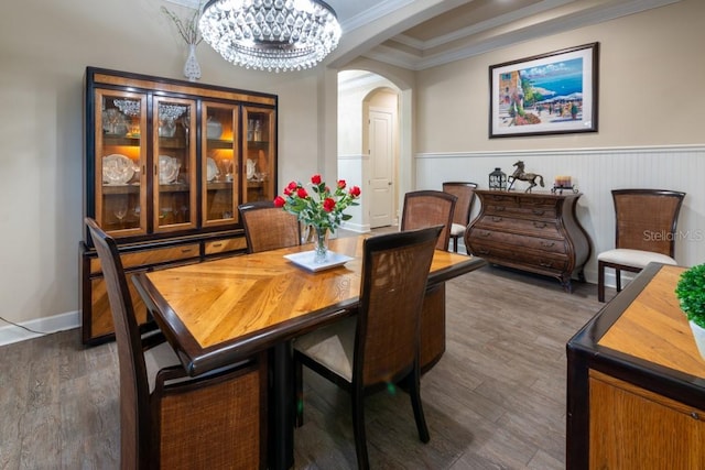 dining space with ornamental molding, dark wood-type flooring, and an inviting chandelier