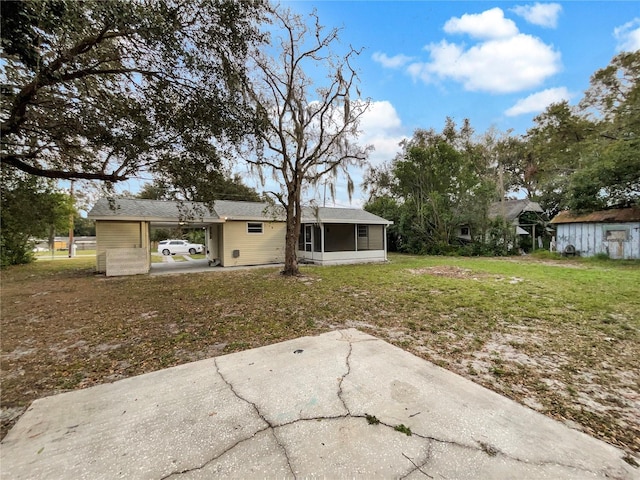 rear view of house featuring a carport, a lawn, and a sunroom