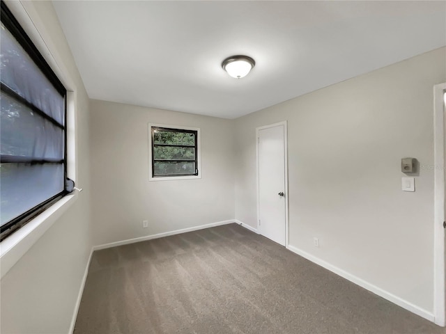 unfurnished room with dark carpet