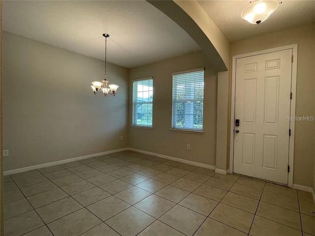 tiled entrance foyer with a chandelier