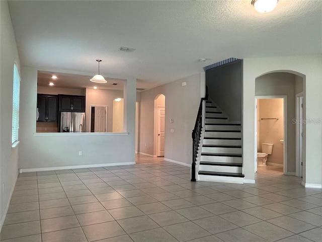 unfurnished living room featuring light tile patterned floors and a textured ceiling