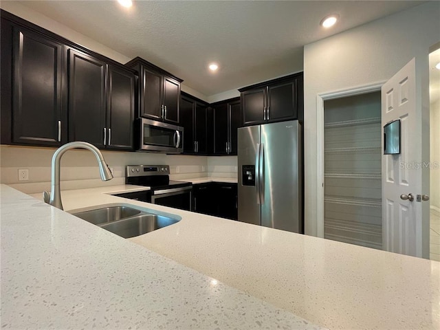 kitchen with light stone countertops, sink, and appliances with stainless steel finishes