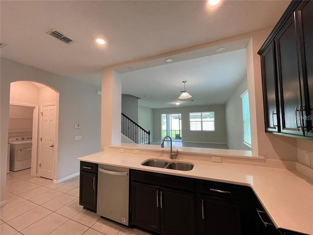 kitchen with sink, stainless steel dishwasher, light tile patterned floors, decorative light fixtures, and washer / clothes dryer