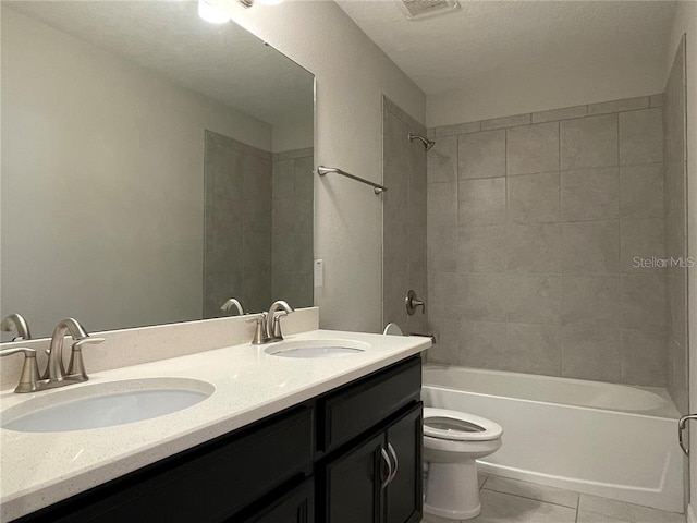 full bathroom with a textured ceiling, vanity, tiled shower / bath combo, tile patterned flooring, and toilet