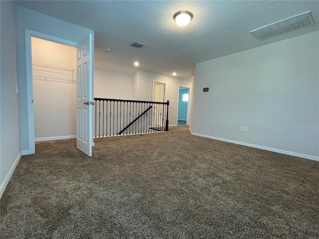 carpeted empty room with a textured ceiling