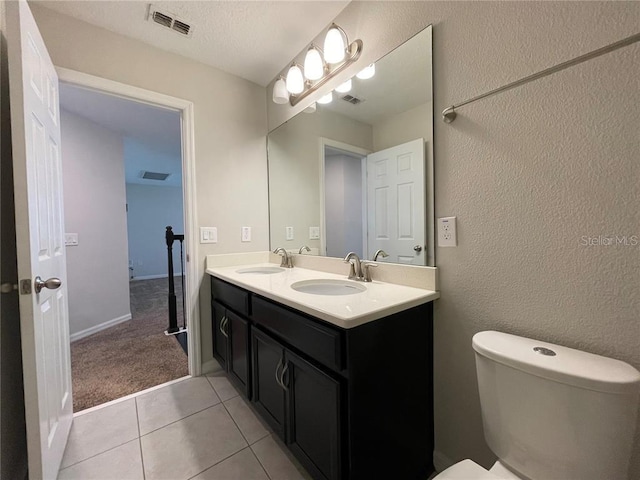 bathroom featuring tile patterned flooring, vanity, a textured ceiling, and toilet