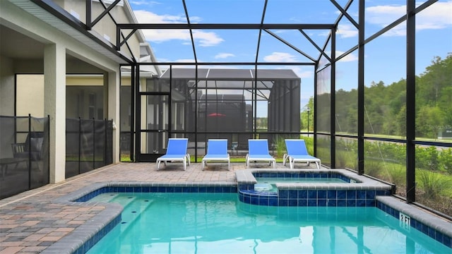 view of pool with glass enclosure, an in ground hot tub, and a patio