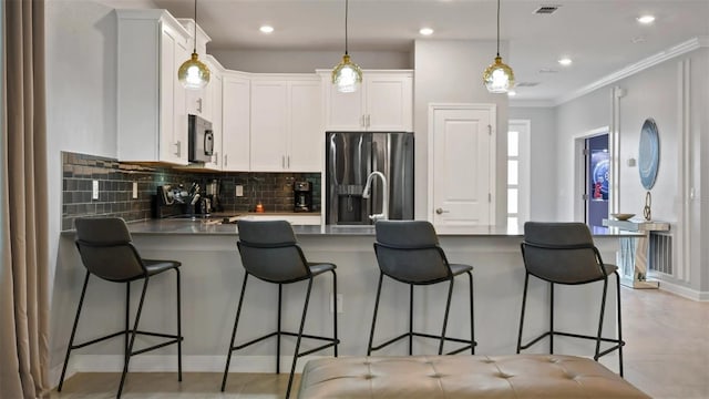 kitchen featuring tasteful backsplash, stainless steel appliances, light tile flooring, hanging light fixtures, and white cabinetry