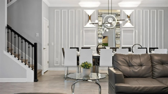 living room featuring a notable chandelier, ornamental molding, and light hardwood / wood-style floors