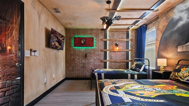 bedroom with brick wall and hardwood / wood-style flooring