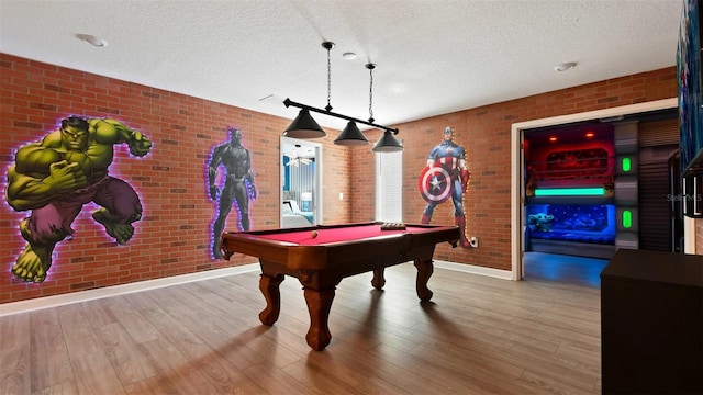 rec room with a textured ceiling, billiards, hardwood / wood-style floors, and brick wall