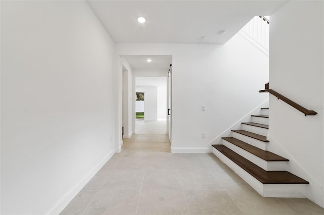 corridor featuring a barn door and light tile patterned flooring