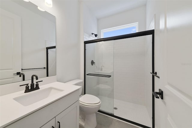 bathroom with tile patterned floors, vanity, toilet, and an enclosed shower