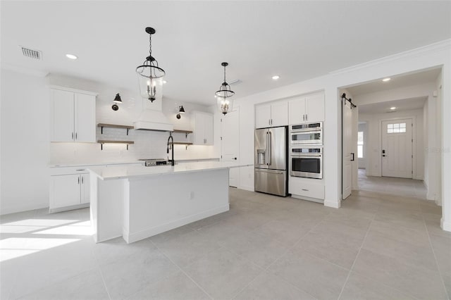 kitchen featuring stainless steel appliances, a kitchen island with sink, and white cabinets