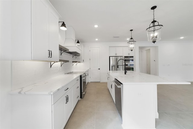 kitchen with pendant lighting, white cabinets, a large island with sink, and appliances with stainless steel finishes