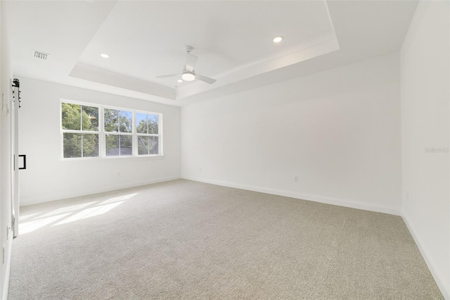 carpeted empty room featuring ceiling fan and a tray ceiling