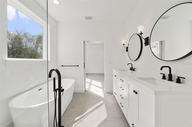 bathroom featuring tile patterned flooring, vanity, and a tub to relax in