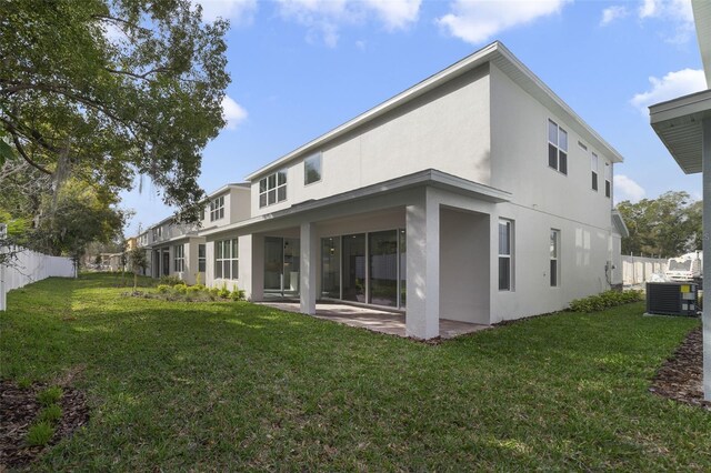 rear view of house featuring cooling unit, a patio area, and a lawn