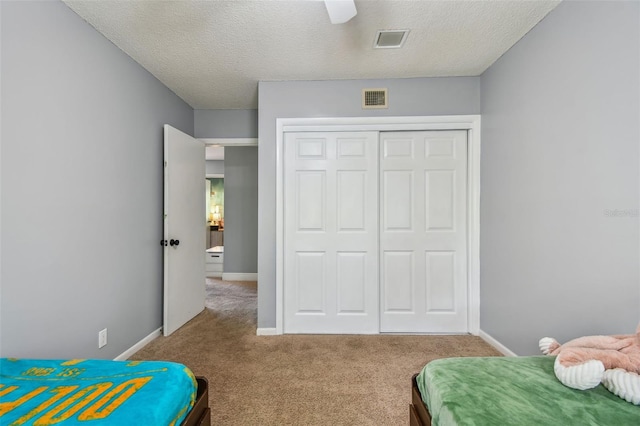 carpeted bedroom with a closet, ceiling fan, and a textured ceiling