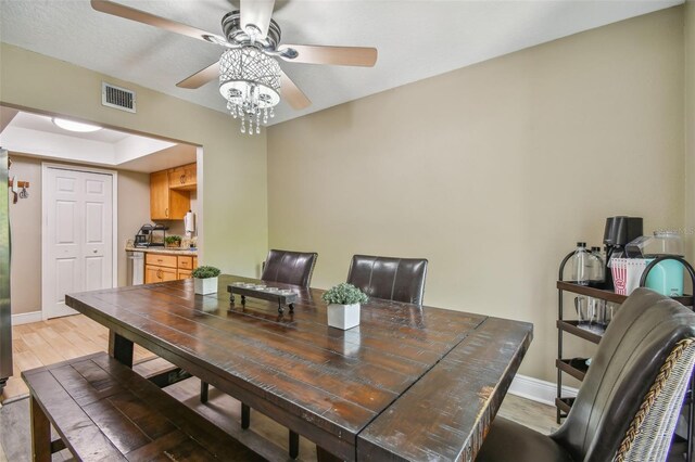 dining space featuring ceiling fan, hardwood / wood-style flooring, and a raised ceiling