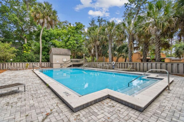 view of swimming pool featuring a storage shed and a patio area