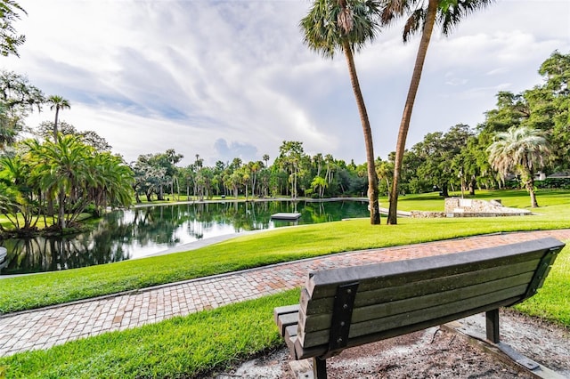 surrounding community with a water view and a yard