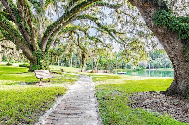 surrounding community with a water view and a yard