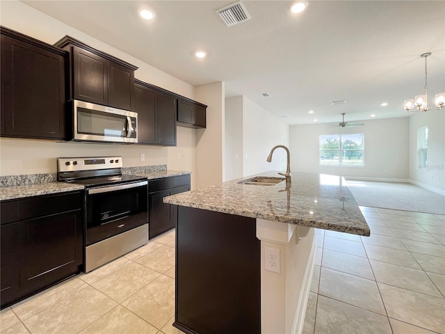 kitchen featuring a center island with sink, ceiling fan with notable chandelier, sink, appliances with stainless steel finishes, and decorative light fixtures