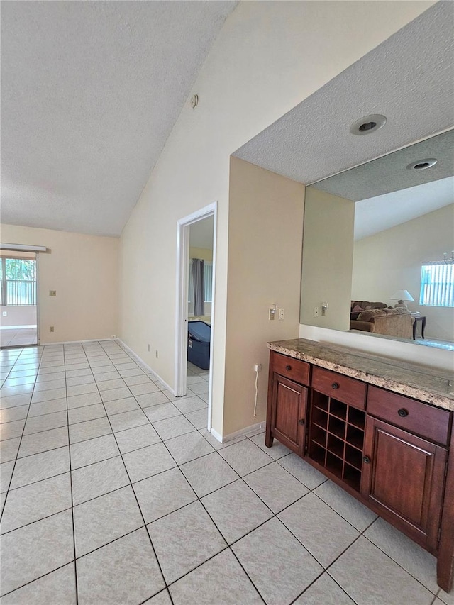 bathroom with tile patterned floors, a textured ceiling, and vaulted ceiling