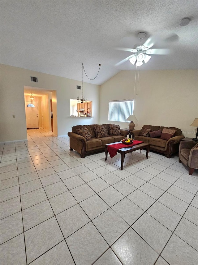 tiled living room with ceiling fan with notable chandelier, a textured ceiling, and vaulted ceiling