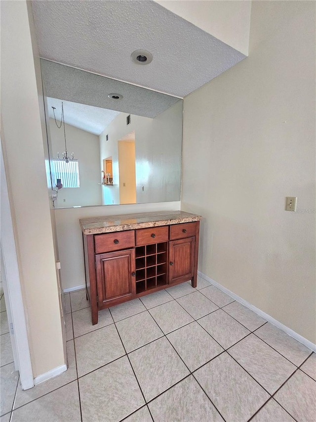 bathroom featuring a notable chandelier, a textured ceiling, and vaulted ceiling