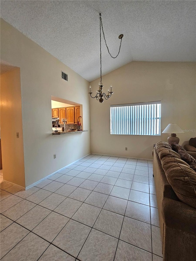 unfurnished living room with a chandelier, light tile patterned floors, a textured ceiling, and vaulted ceiling